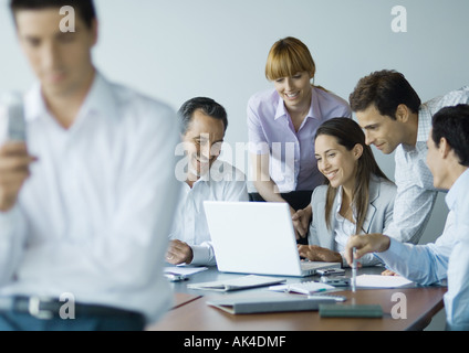 Business colleagues gathered around laptop, smiling Stock Photo