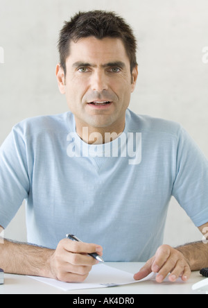 Man writing, looking at camera Stock Photo