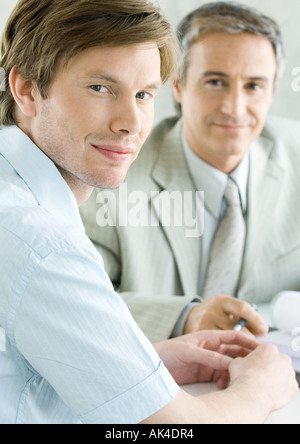 Young man with mature business man, smiling at camera Stock Photo