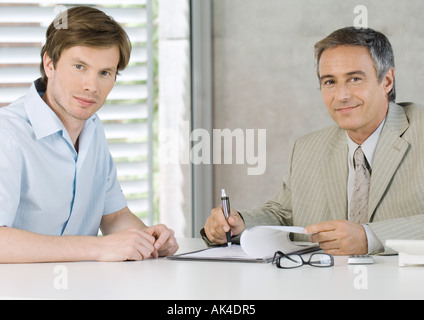 Young man with mature business man, smiling at camera Stock Photo