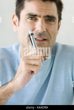 Man holding up pen and looking at camera, close-up Stock Photo