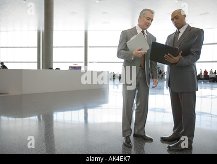 Two businessmen standing and talking in airport concourse Stock Photo