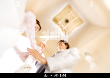 Bride and groom pulling on rope of bell, low angle view Stock Photo