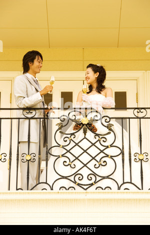 Newlywed couple toasting to each other on balcony Stock Photo