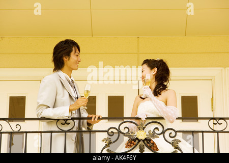 Newlywed couple toasting to each other on balcony Stock Photo