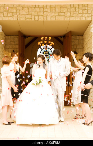 Bride and groom walking out of church, with guests throwing confetti Stock Photo