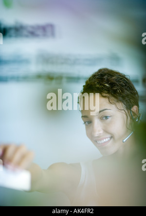 Woman wearing headset and holding out card Stock Photo