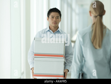 Office worker carrying boxes through corridor