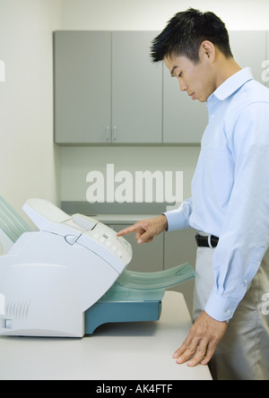 Male office worker using fax machine Stock Photo