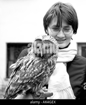 Girl wearing glasses holds a twany owl Strix aluco Stock Photo