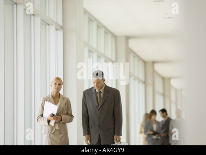 Executives walking through corridor of office building Stock Photo