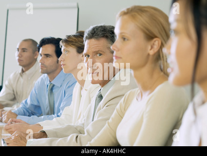 Row of business people, one mature businessman looking at camera Stock Photo