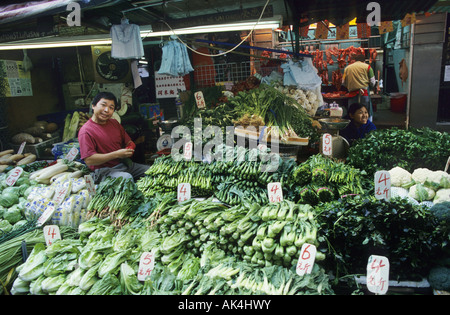 Man at a market stall selling chinese green vegetables in Hong Kong China Stock Photo