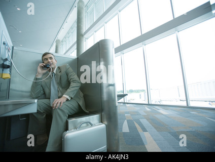 Businessman using pay phone in airport Stock Photo