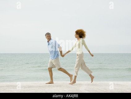 Mature couple running on beach Stock Photo