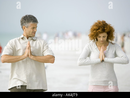 Couple meditating on beach Stock Photo