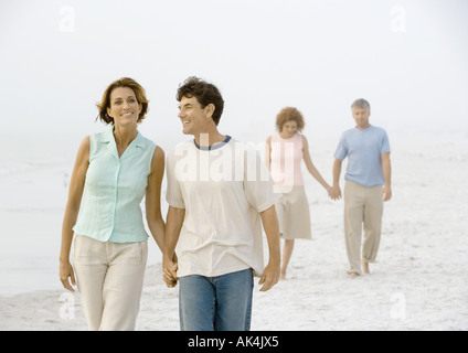 Two mature couples walking on beach Stock Photo