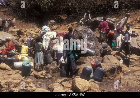 Crowd of Meru people crowd around a tiny spring to collect water Meru district Kenya East Africa Stock Photo