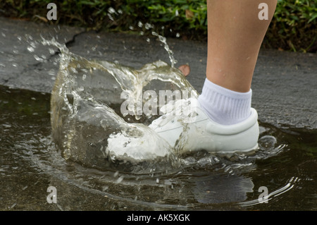 closeup running shoe hitting water puddle Stock Photo
