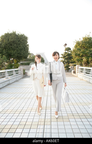 Two female office workers walking along walkway Stock Photo