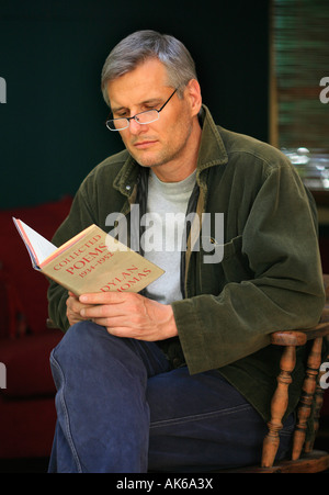 A handsome middle aged man reads poetry by 20th century Irish writer Dylan Thomas Stock Photo