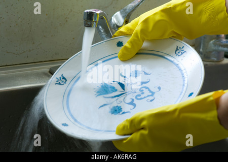 gloved hands washing dishes in kitchen sink Stock Photo