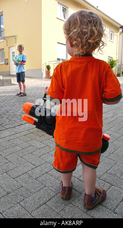 two boys playing with giant water pistols Stock Photo