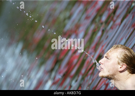 young man squirting water out of his mouth Stock Photo - Alamy