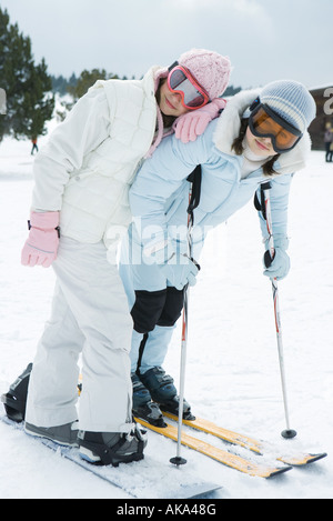 Two young skiers standing together, smiling at camera, one leaning on the other's shoulder, portrait Stock Photo