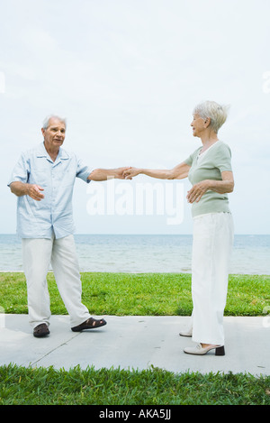 Senior couple dancing on sidewalk overlooking ocean, full length Stock Photo