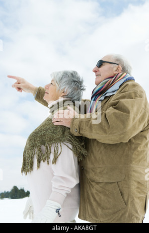 Senior couple standing together, looking up, man pointing Stock Photo