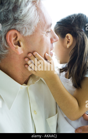 Man holding little girl, girl's hand on man's cheek, close-up Stock Photo