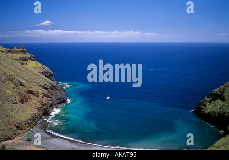 View of El Teide snow peaked mountain on Tenerife from a bay on La Gomera island with a lone yacht Stock Photo