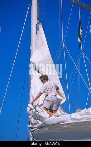 Man on foredeck of yacht handling foresail Stock Photo