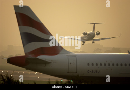 An Air France BritAir Jet comes into land at dawn over the tail of a British Airways Jet waiting for take off at London Gatwick Stock Photo