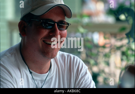 Wearing a cap and sunglasses a handsome bearded man relaxes and enjoys his leisure time Stock Photo