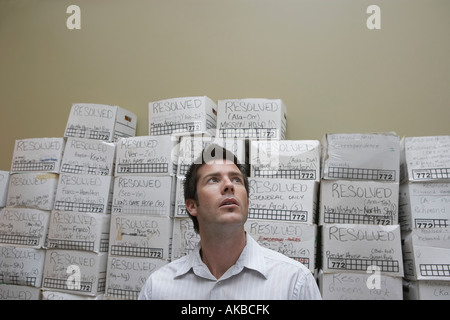 Business man standing in front of stack of filing boxes in storage room, low angle view Stock Photo