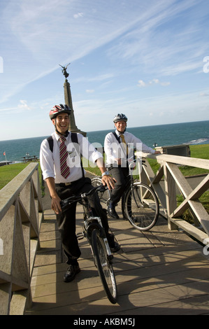 two young male Mormon missionaries with clean white shirts on bicycles in Aberystwyth wearing helmets; summer evening Stock Photo