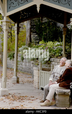 Senior couple laughing together on park bench Stock Photo