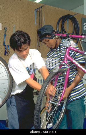 Workers age 15 fixing wheel at Youth Express  bike shop. St Paul Minnesota USA Stock Photo