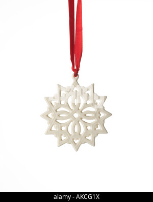 Christmas ornament white stylized porcelain snowflake hanging from red satin ribbon Stock Photo