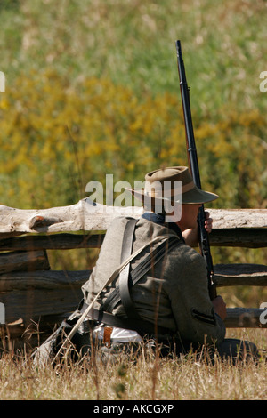 A confederate soldier sitting with a rifle along a fenceline during a battle at an reenactment in Wisconsin Stock Photo