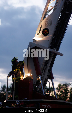 Two firefighters standing at the controls of an extended ladder truck Stock Photo