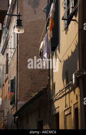 Clean laundry hangs from suspended clothesline outside window of apartment building in Venice Italy Stock Photo