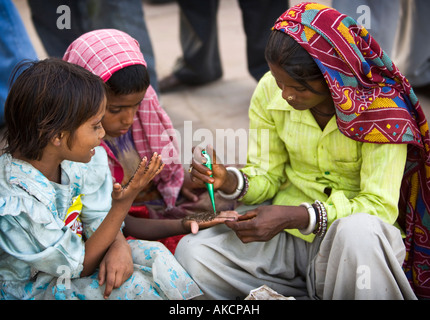 An India lady applying a Henna tattoo to two young girls. India Gate, Delhi, India. Stock Photo
