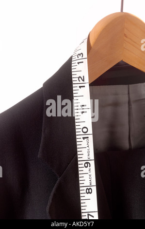 Close up of suit hanging on rail with tailors tape measure - imperial inches measurement showing
