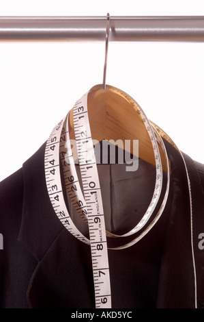 Suit hanging on rail with tailors tape measure wrapped around coathanger