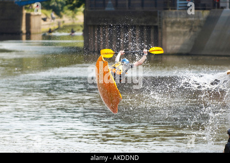 Airborne kayaker in his yellow playboat sliding off a ramp into the river Foss in York. UK Stock Photo