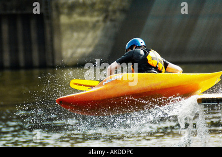 Kayaker in his orange playboat sliding off a ramp into the river Foss in York. UK Stock Photo