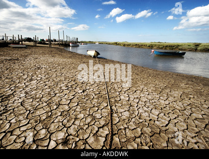 A boat tied up on dried out mud flat with long chain to anchor, Morston Quay 'North Norfolk' UK Stock Photo